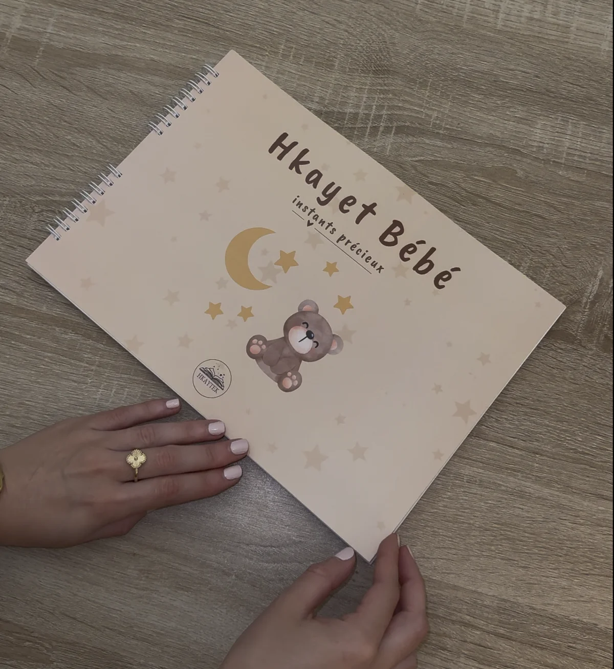 Le livre Hkayet Bébé tenu entre les mains d'une jeune maman
