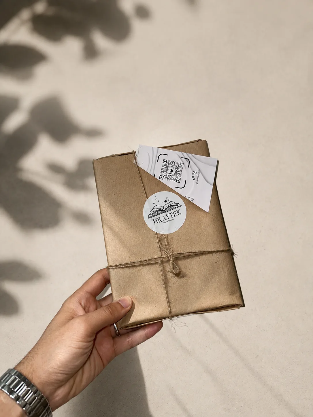Un colis HKAYTEK emballé dans du papier kraft, fermé par une ficelle et un sticker