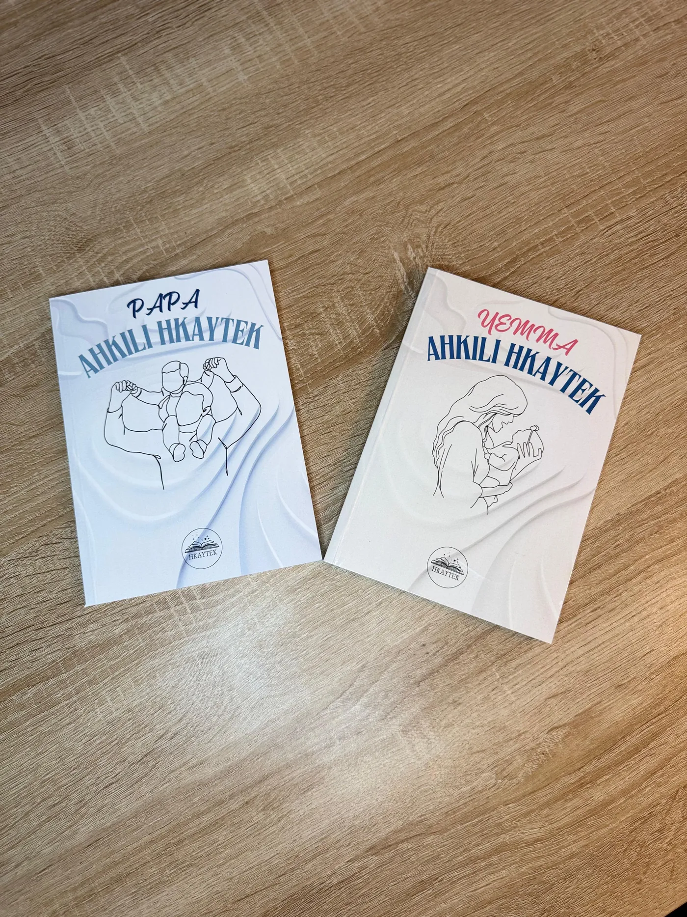 Les livres Papa et Yemma, Ahkili Hkaytek posés côte à côte sur une table en bois