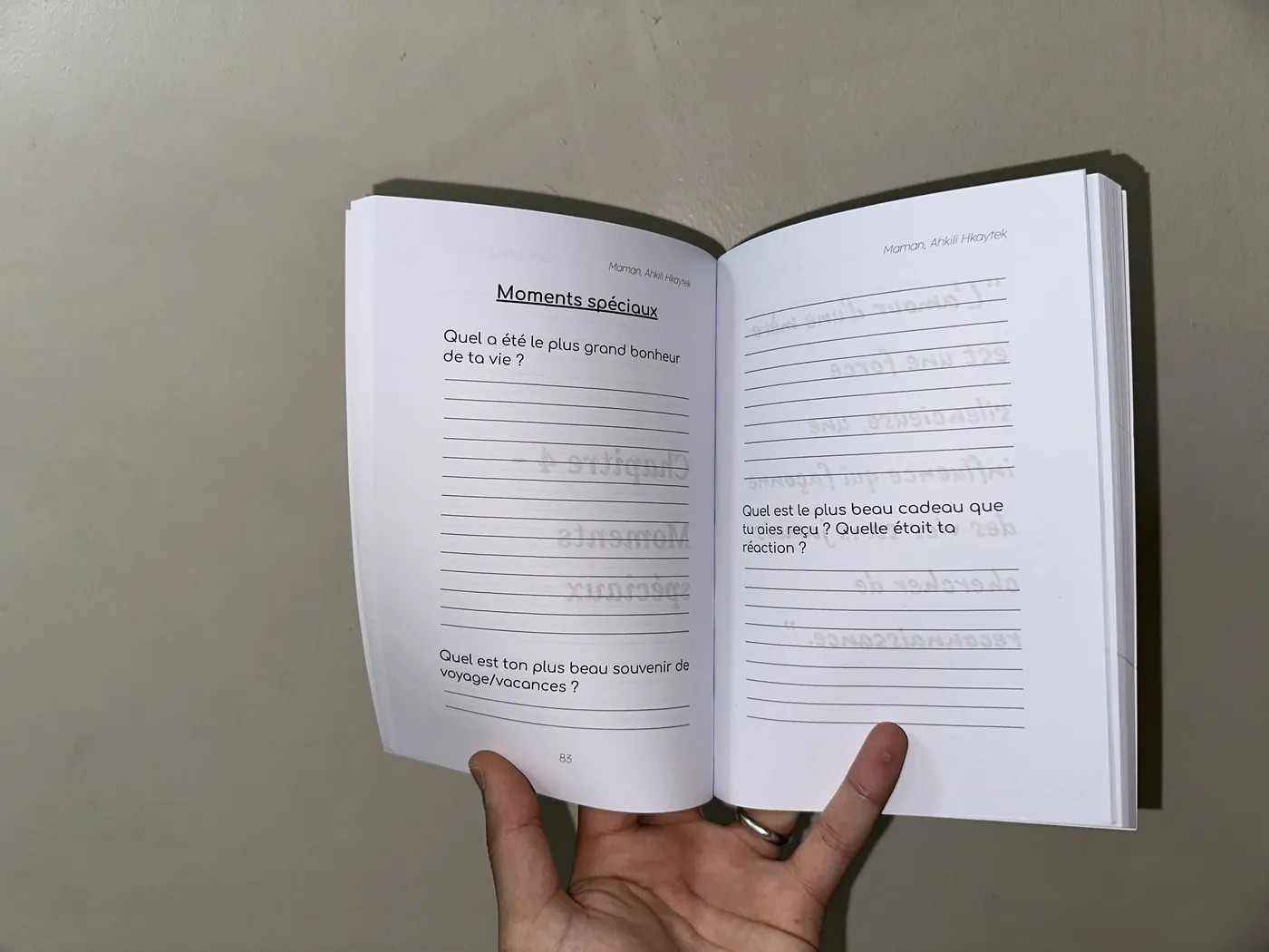 Le livre ouvert à la page 83, tenu dans une main, montrant son épaisseur